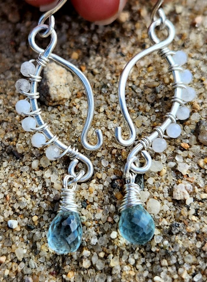 Handmade sterling silver moonstone and aquamarine earrings on beach sand