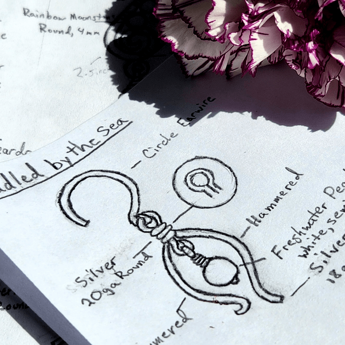 Sea-inspired minimalist jewelry design next to flower.