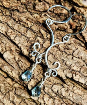 Handmade aquamarine earrings wire-wrapped in sterling silver resting on bark