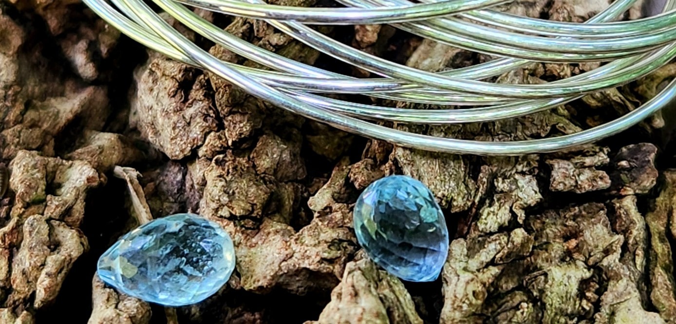 Spring jewelry collection materials with sterling silver and aquamarine on a log