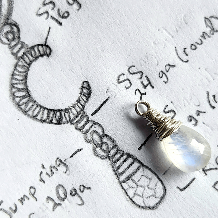 Celestial jewelry design sketch with wire-wrapped rainbow moonstone gemstone on top.