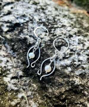 Dainty pearl earrings in sterling silver on a rock