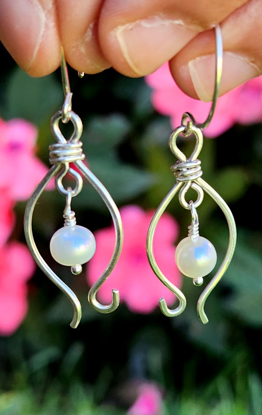 Nature-inspired sterling silver freshwater pearl earrings in front of flowers