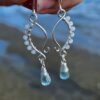 Coastal gemstone earrings with rainbow moonstone wire wrapped and natural aquamarine gemstones on coastal beach