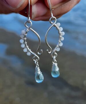 Coastal gemstone earrings with rainbow moonstone wire wrapped and natural aquamarine gemstones on coastal beach