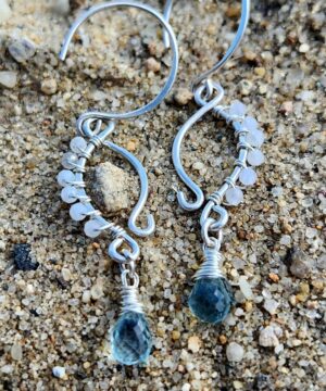 Handmade moonstone earrings with natural aquamarine drops on sandy beach