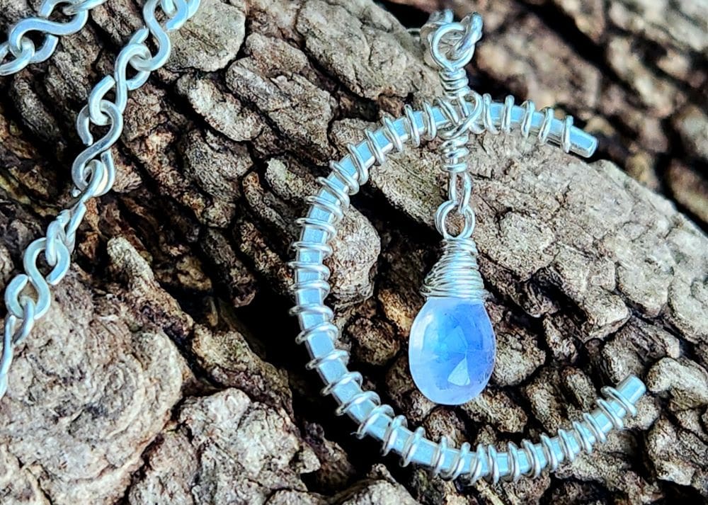 Handmade moonstone jewelry in sterling silver pendant resting on log