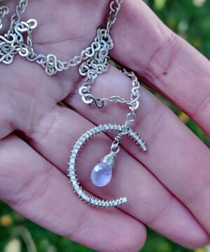 Handmade sterling silver rainbow moonstone pendant resting in hands