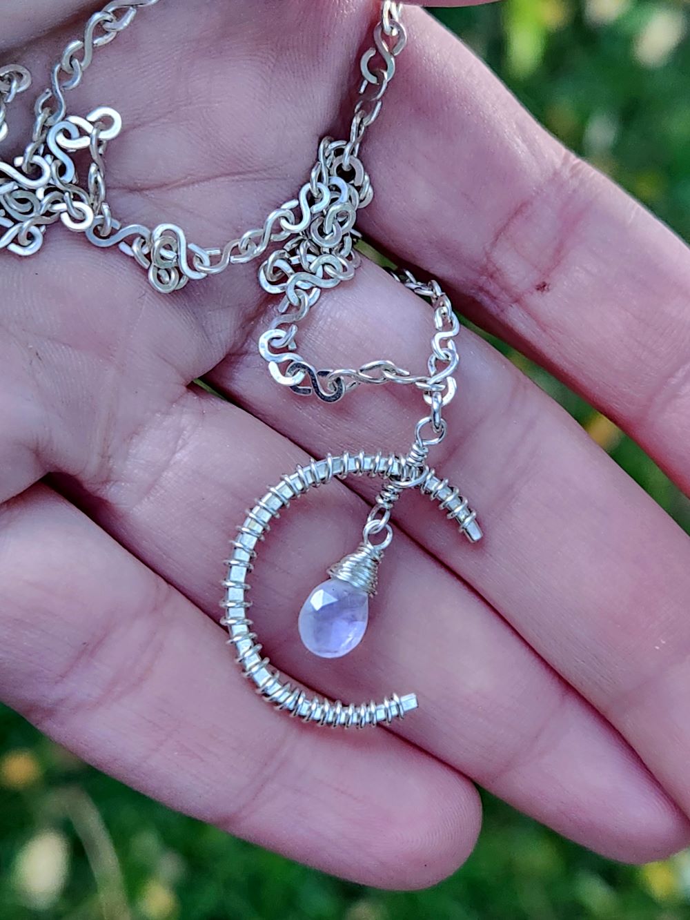 Handmade sterling silver rainbow moonstone pendant resting in hands