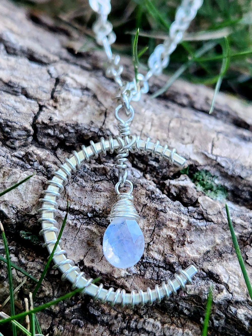 Handmade sterling silver rainbow moonstone pendant resting on wood