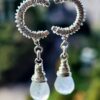 Sterling silver moonstone earrings hanging from window and glowing