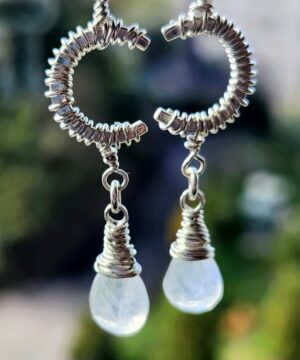 Sterling silver moonstone earrings hanging from window and glowing