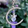 Sterling silver moonstone necklace hanging in front of flowers