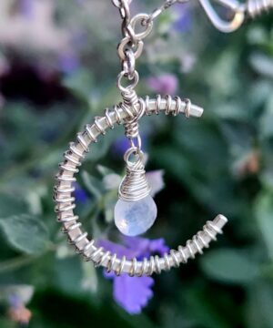 Sterling silver moonstone necklace hanging in front of flowers