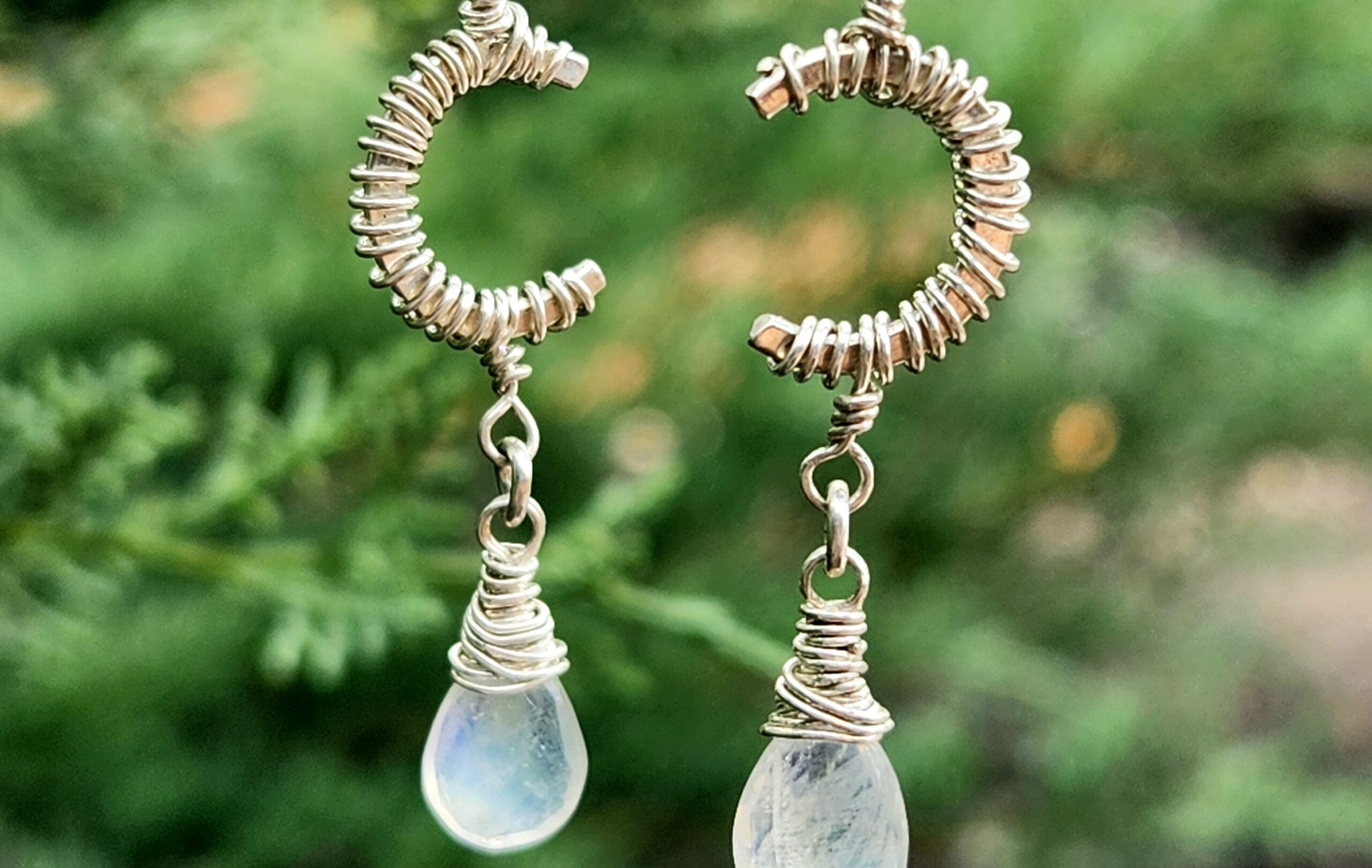 Sterling silver rainbow moonstone earrings dangling from tree in nature