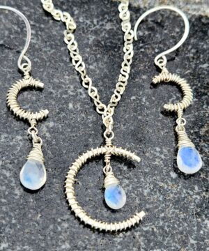 Sterling silver rainbow moonstone jewelry set on rock