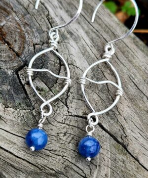 Handmade kyanite drop earrings resting on wood