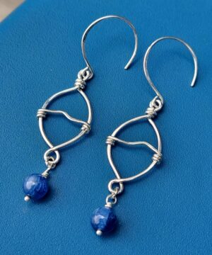 Handmade sterling silver ocean-inspired kyanite earrings on blue background