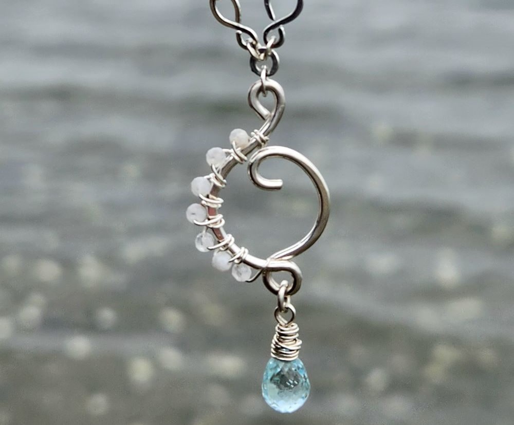 Wire-wrapped rainbow moonstone aquamarine sterling silver pendant at the beach