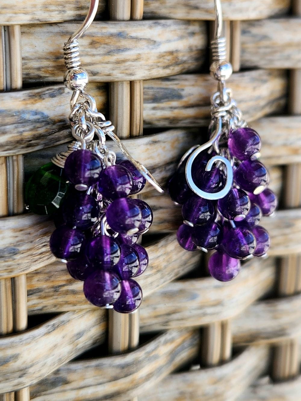 Handmade sterling silver grape earrings hanging on basket