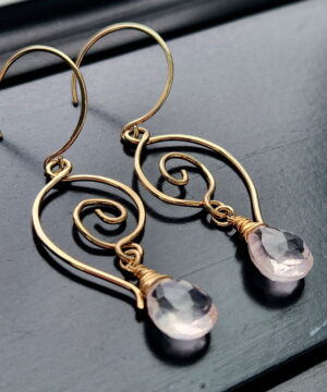 Handmade heart-inspired rose quartz earrings in 14k gold-filled wire on black table