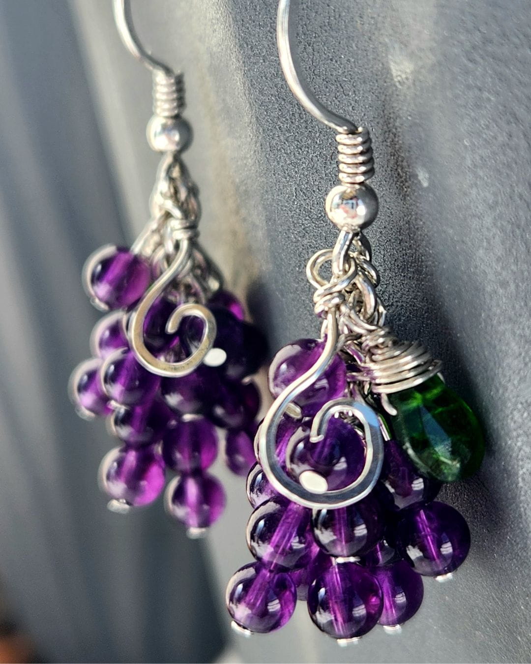 Handmade sterling silver grape earrings hanging on grey pot